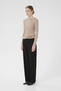 Beige langermet topp i lett materiale, kombinert med høyt liv svarte pinstripede bukser og spisse svarte hæler. Rene linjer gjennom hele antrekket.