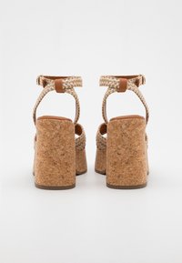 Cork platform sandals with braided textile straps, adjustable ankle buckle, and a wide heel. Features a textured cork surface.