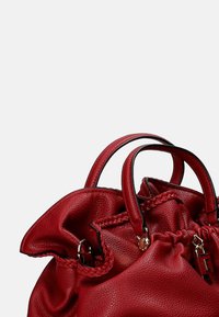 Borsa a tracolla in pelle rossa con superficie testurizzata, parte superiore arricciata, doppi manici e dettagli intrecciati intricati. Rifinita con accenti in hardware dorato.