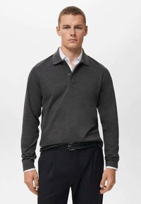 Polo de manga larga gris oscuro con cuello, que presenta una tapeta abotonada y un detalle en el interior del cuello en blanco, combinado con pantalones oscuros.