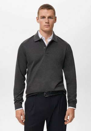 Polo de manga larga gris oscuro con cuello, que presenta una tapeta abotonada y un detalle en el interior del cuello en blanco, combinado con pantalones oscuros.