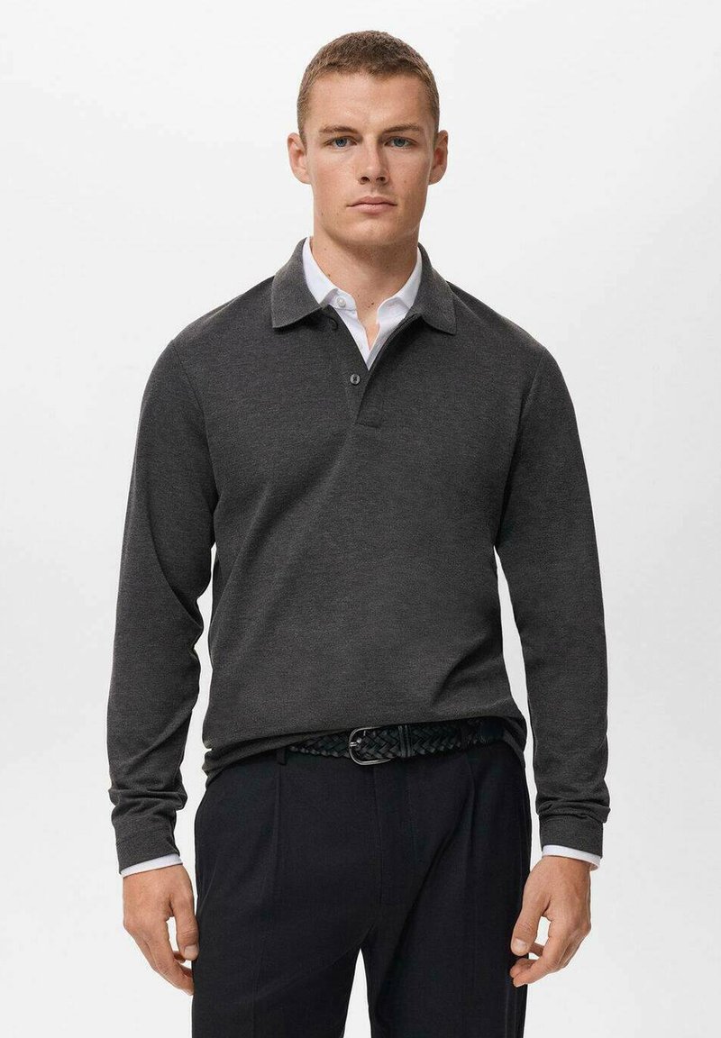 Polo de manga larga gris oscuro con cuello, que presenta una tapeta abotonada y un detalle en el interior del cuello en blanco, combinado con pantalones oscuros.