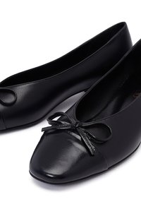 Ballerine nere con una tomaia in pelle liscia, punta affilata e un fiocco decorativo sul davanti. Design minimalista con una finitura opaca.