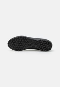 Suela de zapato de goma negra con un patrón hexagonal para tracción, superficie lisa con un logo de la marca embellecido en el centro.