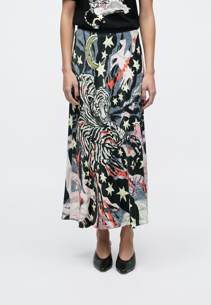 Maxi sukňa v čiernej farbe s farebnými vzormi zvierat a hviezd, z hodvábnej látky a s prúdiacim dizajnom. Kombinovaná s čiernymi topánkami s ostrou špičkou.