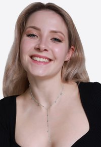 Sølv halskæde med et Y-formet design, der har cirkulære accenter langs en delikat kæde. Modellen har en sort top på og smiler.