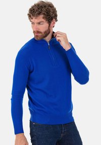 Pull bleu à col zippé avec poignets et ourlet côtelés. Fabriqué en tissu doux, il présente une fermeture à demi-zip et une texture lisse.