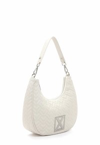 Witte, gewatteerde handtas met een gebogen vorm, voorzien van een zilveren logo-accent en een ritsluiting. De schouderband is verstelbaar en heeft zilveren hardware.