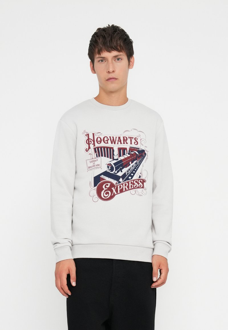 Lys grå hettegenser med en vintage-stil "Hogwarts Express" grafikk i rødt og blått. Ribbestrikkede ermer og hem, laget av mykt bomullsmateriale.
