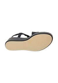 Sandal nera con suola piatta, caratterizzata da una suola esterna marrone chiaro con texture e un design di cinturino semplice.