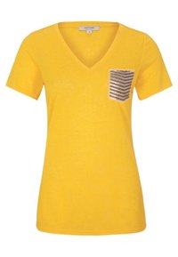 T-shirt à col en V jaune en tissu doux, avec un détail de poche rayée marron et blanche sur le côté gauche de la poitrine. Manches courtes.
