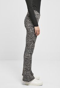 Leggings grigi con un motivo a strisce zebrate nere, realizzati in tessuto elastico, dotati di una vita comoda e di un design con orlo svasato.