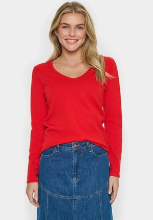 Rode, lange mouwen V-hals trui gemaakt van zachte gebreide stof, gecombineerd met een denim rok met patchwork ontwerp en een voorste knoopsluiting.