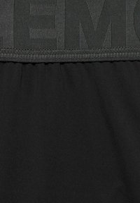 Zwarte sportieve broek met een gestructureerde tailleband met reliëfletters en een glad, lichtgewicht materiaal met geplooide details.