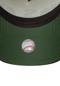 Gorra de béisbol con un cuerpo de tela verde oscuro y visera negra. Presenta una etiqueta circular con un gráfico de béisbol y texto impreso.