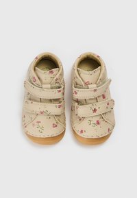 Bēšas ādas kurpes ar rozā ziedu rakstiem, dubultām Velcro aizdares siksnām un brūnām gumijas zolēm, arapaļām purngalām un šuvju rotājumiem.