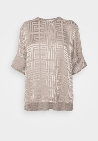 Blusa a maniche corte in seta beige chiaro con un sottile motivo geometrico. Design squadrato e scollatura rotonda, con maniche ripiegate.