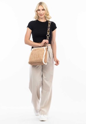 Borsa a tracolla in suede marrone con rifiniture in pelliccia bianca, tracolla con motivo e forma rettangolare. Presenta una chiusura a pattina e un marchio sottile.
