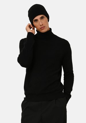 Svart polotröja i mjukt material, med långa ärmar och en åtsittande design, matchad med en ribbad mössa.