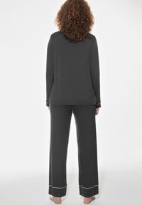 Grijs long-sleeve top en bijpassende broek, gemaakt van zachte stof, met een ontspannen pasvorm, met roze stiksel langs de manchetten en zoom.