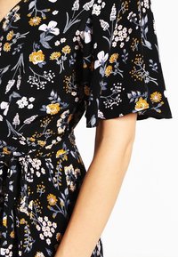 Vestido negro con estampado floral en amarillo, blanco y gris, con mangas cortas tipo volante y un cinturón de tela atado en la cintura.