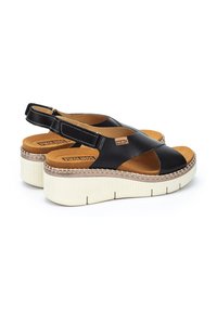 Sandalias de plataforma de cuero negro con diseño tipo slingback, que cuentan con una plantilla acolchada, una media suela trenzada y una suela blanca texturizada.