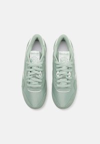 Light green Reebok sneakers with a smooth fabric and suede finish, featuring white accents, round laces, and a padded collar.