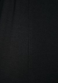 Schwarzer Textilstoff mit glatter Textur und leichtem Glanz, der entlang der Seite eine subtile Nahtdetails aufweist.