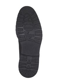 Suola di scarpa in gomma nera con una superficie testurizzata. I contorni includono motivi in rilievo per la trazione, compresi design circolari e lineari.