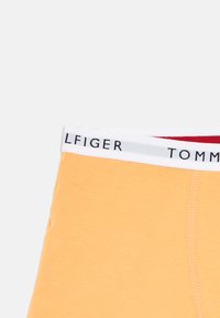 Narancssárga pamut boxeralsó fehér derékrésszel, fekete és piros "TOMMY HILFIGER" logó felirattal és varrási részletekkel.