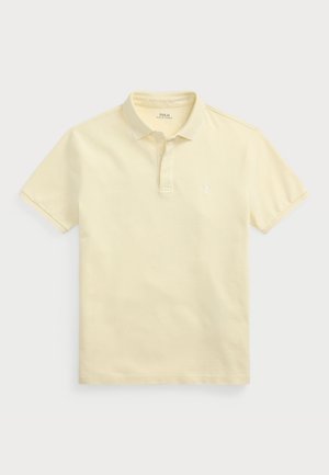 Polo majica iz svetlo rumenega bombažnega blaga s kratkimi rokavi, ovratnikom in gumbom s tremi gumbi. Ima majhen logotip na levi strani prsnega koša.