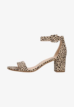 Beżowe sandały na kostkę z paskiem z blokowym obcasem, z nakładającym się wzorem w czarne kropki, szeroką wkładką i gładką teksturą. Z detalem zapięcia na klamrę.