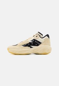Beige og sort sneakers med en overdel i ruskind, præget af en glat sort sidepanel med hvide prikker og en struktureret gummisål.