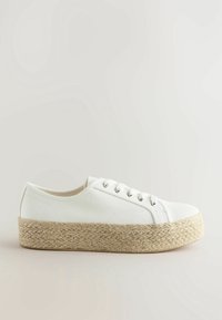 White canvas sneaker with a round toe, featuring a woven jute platform sole. Five eyelet lace-up design and smooth texture.