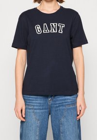 Marineblauw katoenen T-shirt met korte mouwen, voorzien van het woord "GANT" in contrasterende witte borduursel over de borst, eenvoudige ronde hals.
