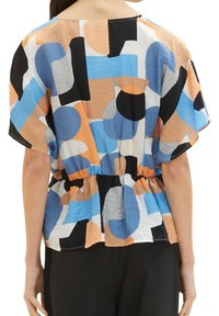 Blusa a maniche corte con un motivo geometrico multicolore che presenta cerchi e linee. Vita elastica e vestibilità ampia. Realizzata in tessuto leggero.