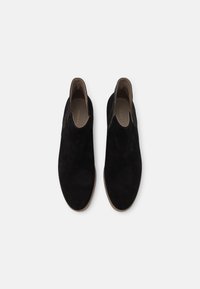 Bottines en daim noir à texture lisse, avec des panneaux latéraux élastiques et un bout arrondi, dotées d'une semelle en caoutchouc de couleur claire.