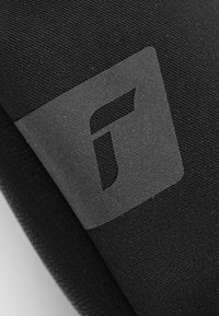 Schwarzes Textilmaterial mit einer glatten, matten Oberfläche. Enthält ein klares Logo in der Ecke, das teilweise transparent gegen den Stoff ist.
