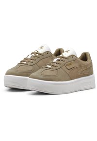 Beige semišové tenisky s bílou gumovou platformou, plochými tkaničkami a zlatým logem na jazyku a boku. Jemné detaily stehování jsou viditelné.