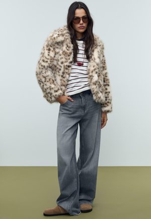 Nepalen leopardenprint jack, wit en marineblauw gestreept shirt, grijze wijde jeans en bruine instappers, met overgrote zonnebril.
