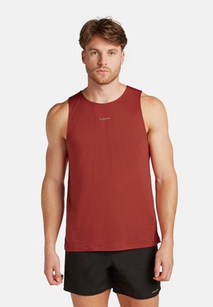 Haut de sport sans manches rouge avec une finition texturée et un col rond, arborant un petit logo sur la poitrine. Porté avec un short noir.