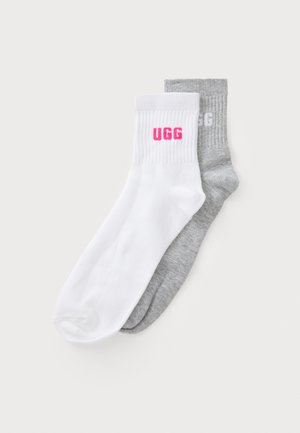 Dva para crew čarapa: jedan bijeli s ružičastim UGG logotipom, drugi sivi s sivim UGG logotipom, s rebrastim manžetama i mekanom teksturom.