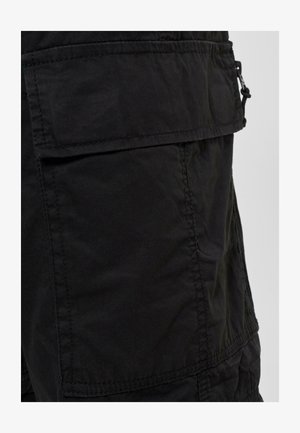 Black cargo shorts made of durable fabric, featuring a front pocket with a flap, and visible stitching details. Smooth texture.