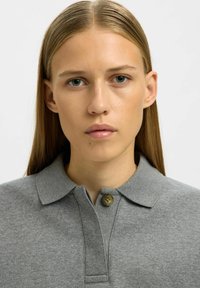 Hall hall polo-särk kraega, lühikese plaketiga ja ühe nupuga. Sile tekstuur, mitteametlik disain ja neutraalne värv, sobib erinevate rõivastega.