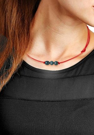 Collier à cordon réglable rouge comportant trois perles rondes bleu foncé, présentant une texture lisse et un design minimaliste.