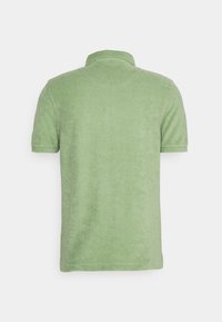 Kortärmad ljusgrön polotröja med krage, visad från baksidan på en neutral vit bakgrund.