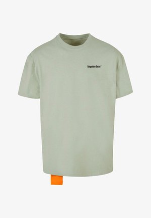 Tricou din bumbac de culoare verde deschis, cu guler rotund și mâneci scurte. Prezintă un mic logo negru pe față și o etichetă portocalie la baza tricoului.