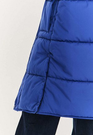 Niebieska pikowana kurtka puchowa z teksturą pikowaną, wyposażona w zatrzaski na dolnym brzegu i lekko rozkloszowany fason. Materiał wydaje się lekki.