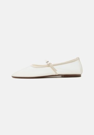 Chaussure plate Mary Jane blanche avec bout pointu, fine bride réglable avec boucle argentée, et semelle marron sur fond blanc.