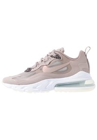 Light pink athletic shoe with mesh and suede materials, rounded shape, visible air unit in translucent sole, and subtle design accents.
